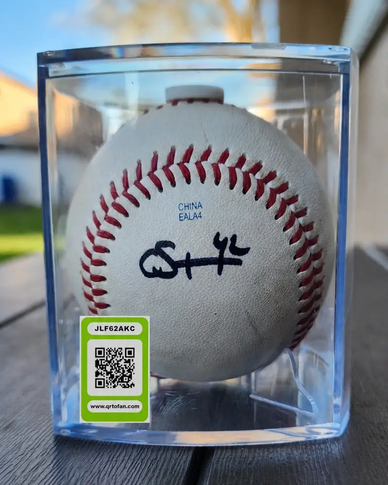 A signed baseball in a display case with a QRTOFAN tag